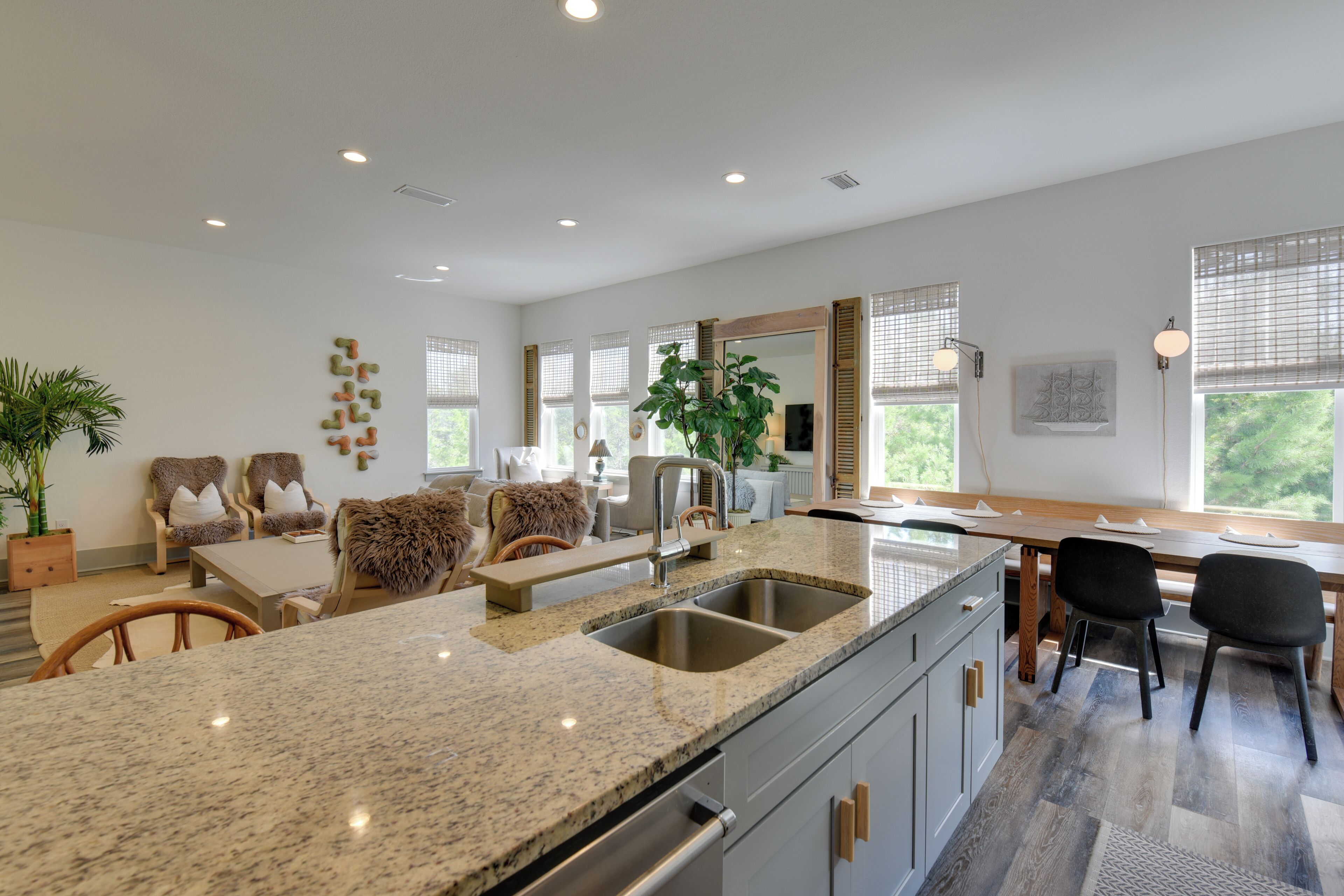 A modern kitchen with granite countertops, a double sink, and a dining area with a wooden table and chairs.