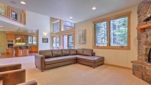 A spacious living area with a large sectional sofa, a stone fireplace, and a kitchen in the background. - Close to Slopes: Forest-view Gem in Lake Tahoe (South Lake Tahoe)