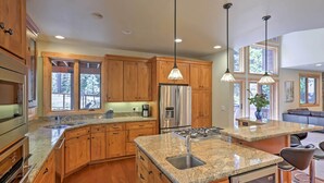 A spacious kitchen with wooden cabinets, granite countertops, stainless steel appliances, and pendant lighting. - Close to Slopes: Forest-view Gem in Lake Tahoe (South Lake Tahoe)