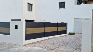 A modern building with a white exterior, a black and wooden gate, and a small window.