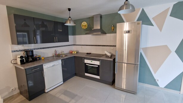 A modern kitchen with a dishwasher, a stainless steel refrigerator, and a microwave.