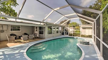 Une piscine couverte avec un espace patio, des chaises et une vue sur le jardin arrière.
