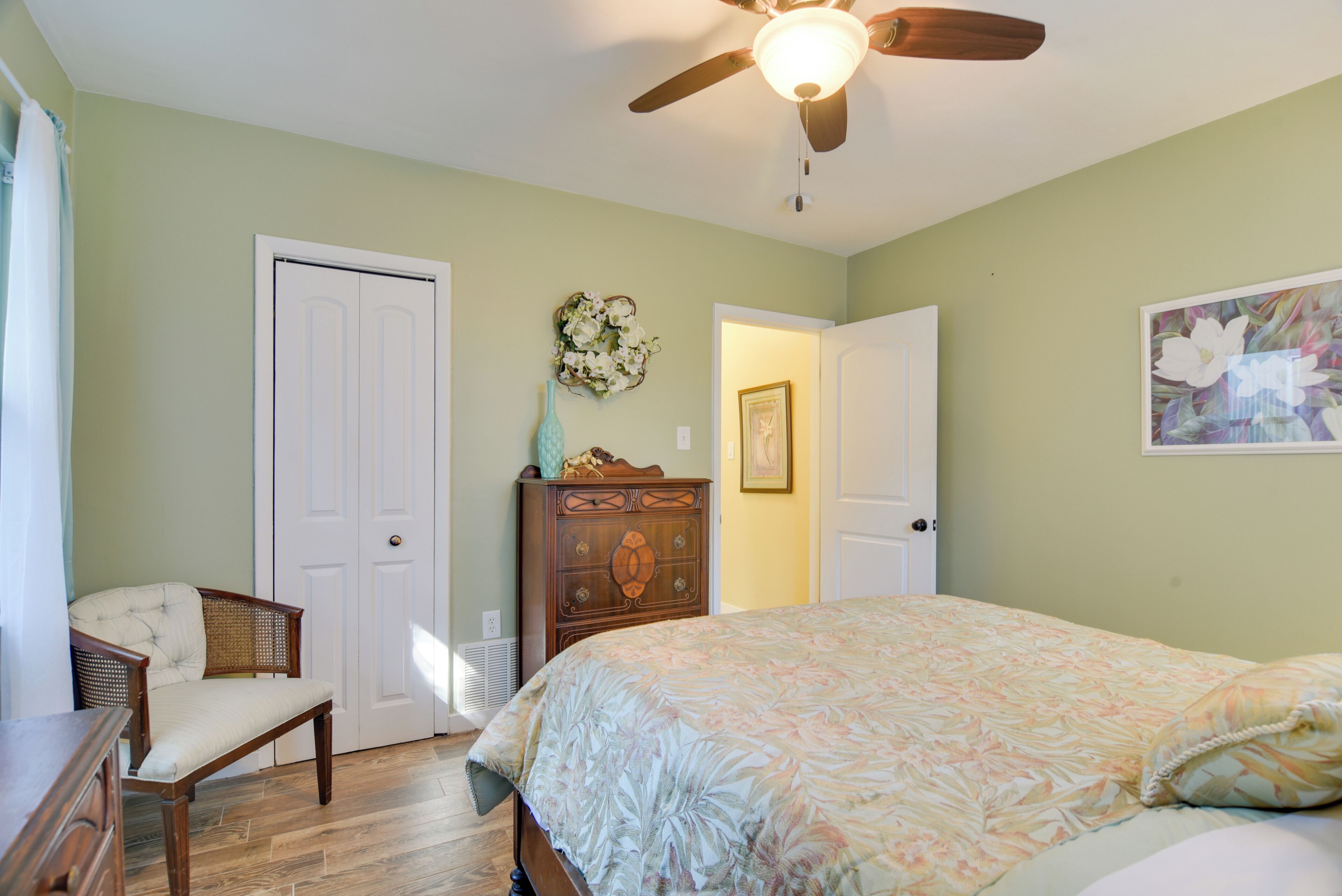 A bedroom with a bed, a chair, a dresser, and a ceiling fan.