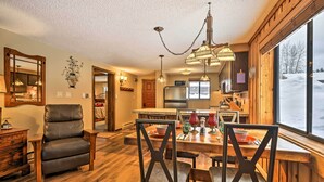 A wooden interior with a dining area, leather chair, and a large window. - Gorgeous Winter Park Condo w/ Private Deck! (Winter Park)