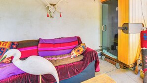A room with a wooden ceiling, a glass door, a wooden wardrobe, and a colorful sofa with a white bird decoration. - Adobe Studio: 2 Blocks to Dtwn Santa Fe Plaza! (Santa Fe)