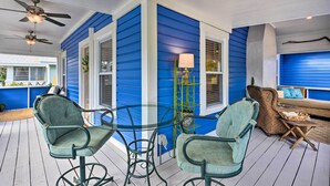 A covered outdoor seating area with two chairs and a glass table, blue siding, and a ceiling fan. - Bright Bradenton Retreat: 1 Mi to Downtown! (Bradenton)