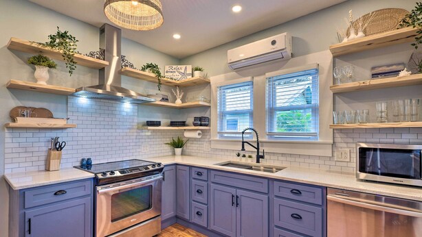 A modern kitchen with a stainless steel stove, a built-in oven, a sink, and wooden shelves with plants. - Bright Bradenton Retreat: 1 Mi to Downtown! (Bradenton)
