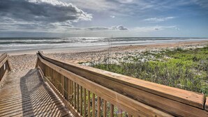 A wooden boardwalk leading to a beach with a view of the ocean and overcast sky. - Oceanfront Condo Rental Near Daytona Speedway (Ormond Beach)