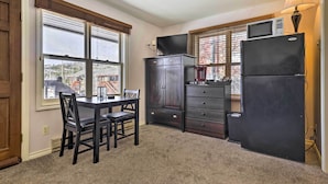A compact kitchen with a dining table, dark wooden cabinets, a refrigerator, and a microwave. - 3 Mi to National Park: Cozy Studio in Grand Lake (Grand Lake)