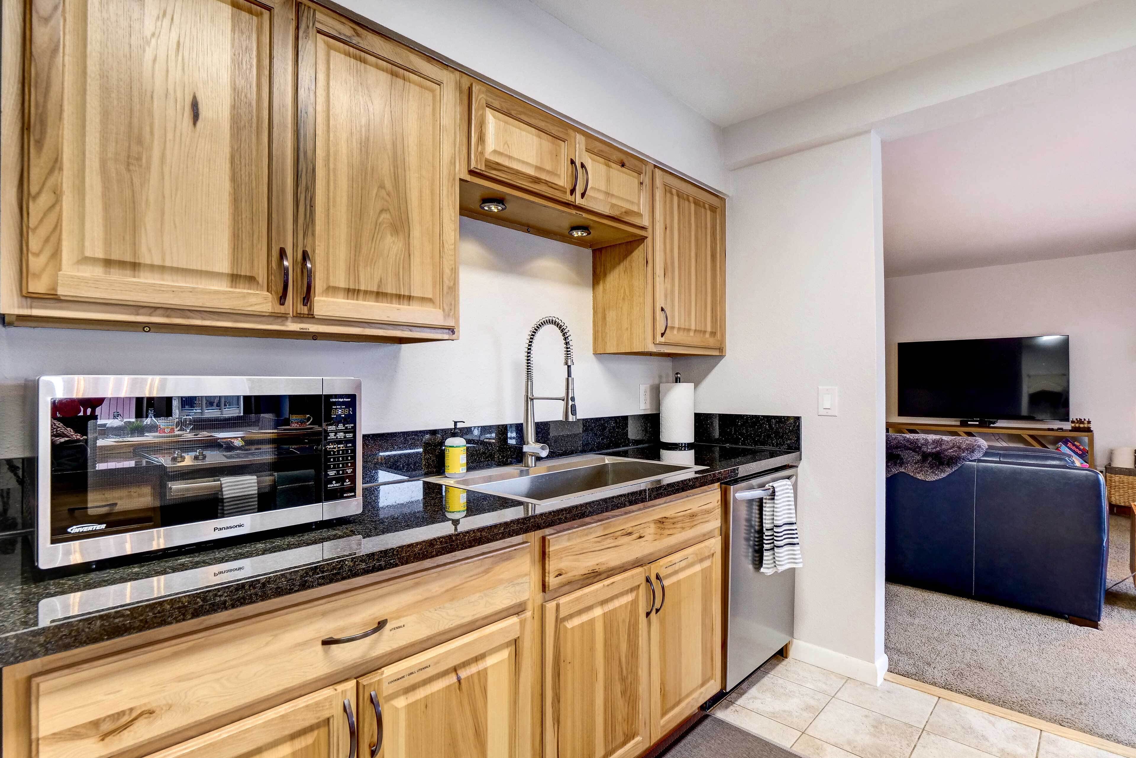 A modern kitchen with wooden cabinets, a stainless steel sink, and a built-in microwave.
