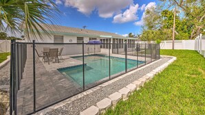 Una piscina con cerramiento de vidrio, rodeada por un borde de piedra y un césped.