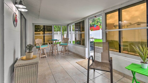 Un patio cubierto con mobiliario de mimbre, una mesa verde y una planta en maceta.