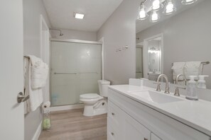 A modern bathroom with a glass-enclosed shower, a white toilet, and a vanity with a large mirror and multiple faucets. - Kodak Getaway w/ Covered Decks + Game Room! (Kodak)