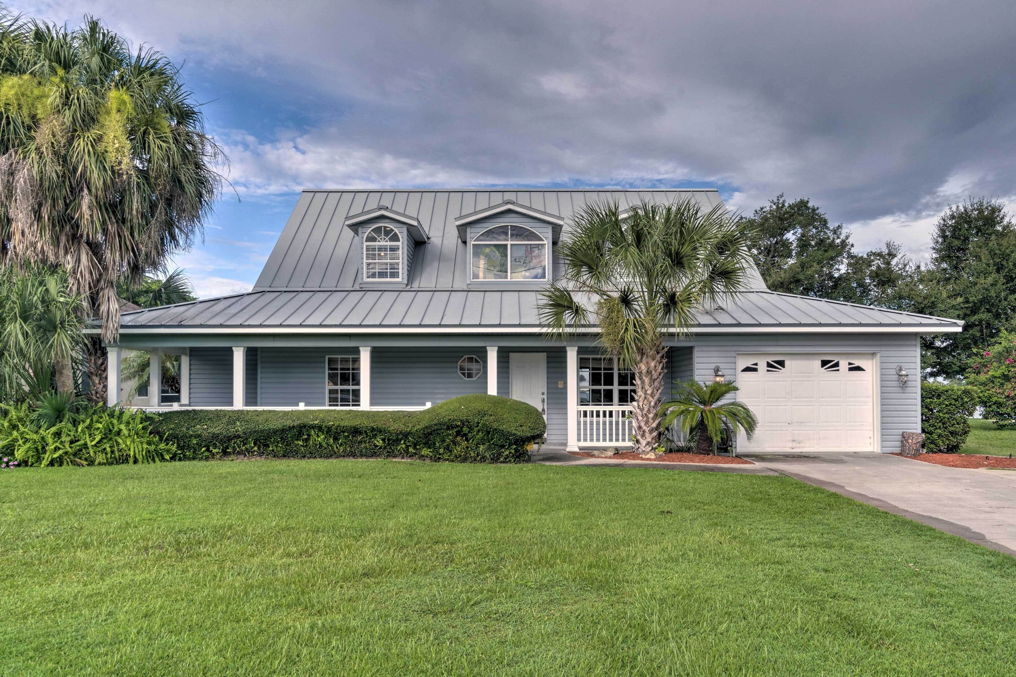 A two-story house with a grey metal roof, a front porch, and a garage.