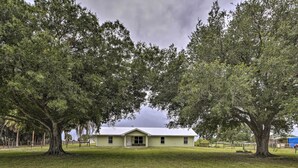 A single-story house with a flat roof, surrounded by a well-maintained lawn and large trees.