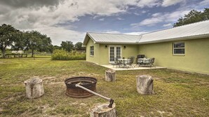A house with a green exterior, a patio with outdoor furniture, and a metal roof.