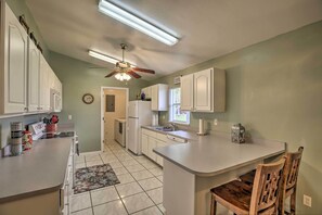A kitchen with white cabinets, a central island, a ceiling fan, and a window. - Lake Okeechobee Fishing Retreat w/ Fire Pit! (Clewiston)