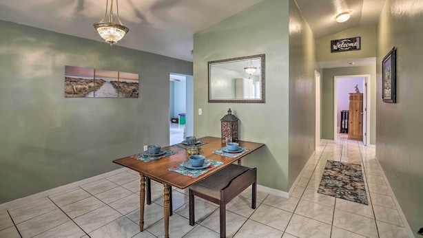 A dining area with a table set for four, a chandelier, a mirror, and a 'Welcome' sign on the wall.