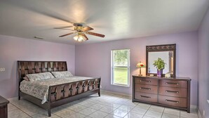 A bedroom with a bed, a dresser, a ceiling fan, a window, and a mirror.