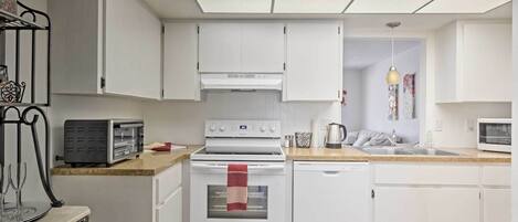 Une cuisine moderne avec des meubles blancs, un four encastré, un four à micro-ondes et un grille-pain.
