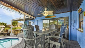 An outdoor patio with a pool, a table with chairs, and a ceiling fan. - Canal-front Oasis w/ Dock & Kayaks in Cape Coral! (Cape Coral)