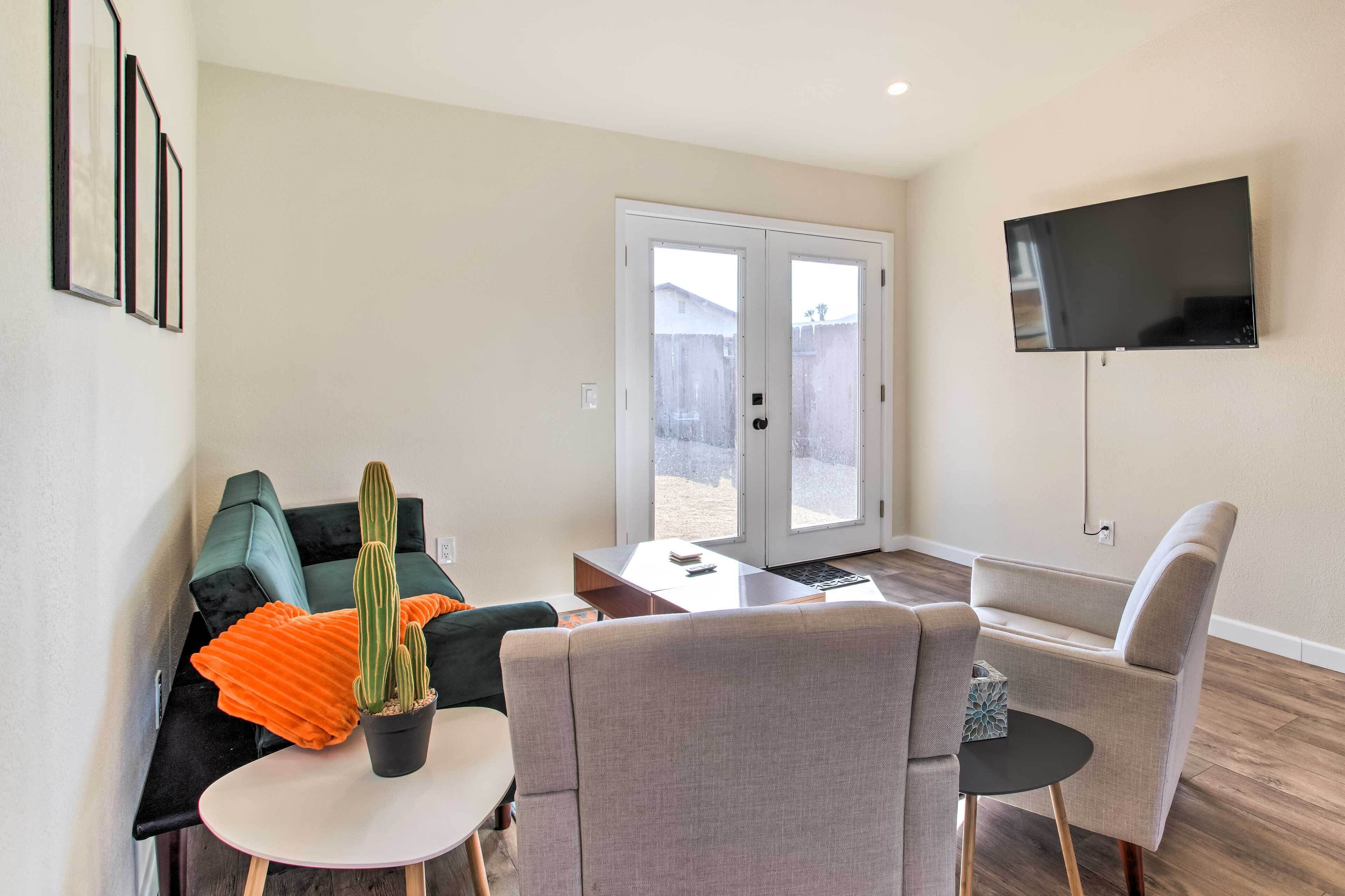A modern living room with a sofa, armchairs, a coffee table, and a TV mounted on the wall.