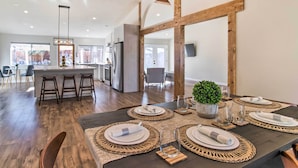 A modern dining area with a dark wooden table set for four, surrounded by woven placemats and white plates. - 2 Mi to Coachella: Indio Getaway w/ Outdoor Oasis! (Indio)