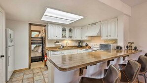 A modern kitchen with white cabinets, a wooden countertop, and bar stools. - Walk to Ski Lift: Breckenridge Retreat w/ 2 Decks! (Breckenridge)