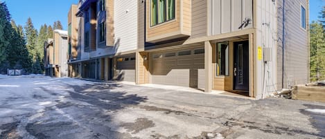 Un edificio residencial de varios pisos con garaje, ventanas amplias y entrada para vehículos.