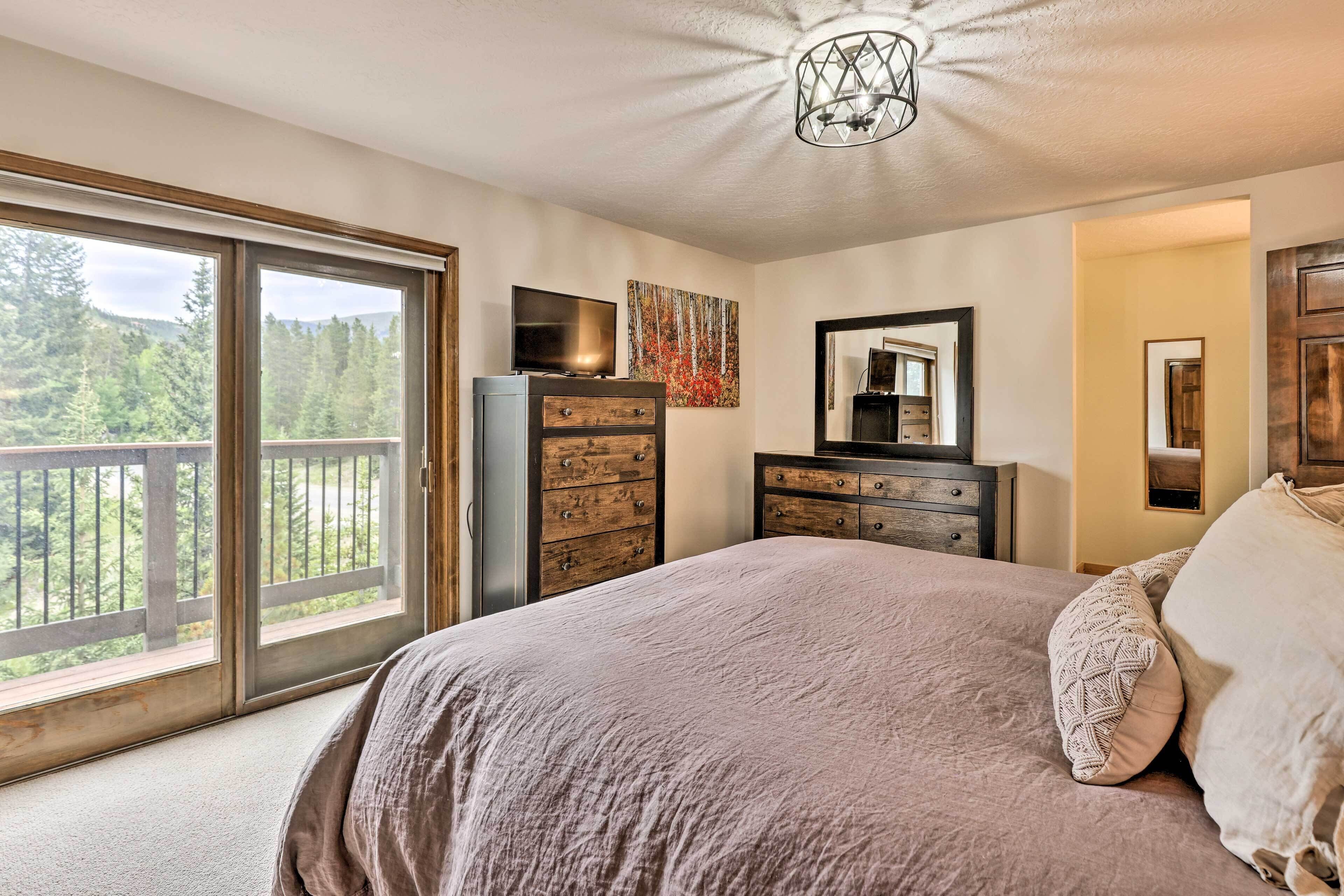 A bedroom with a large bed, a dresser, a television, and a painting.