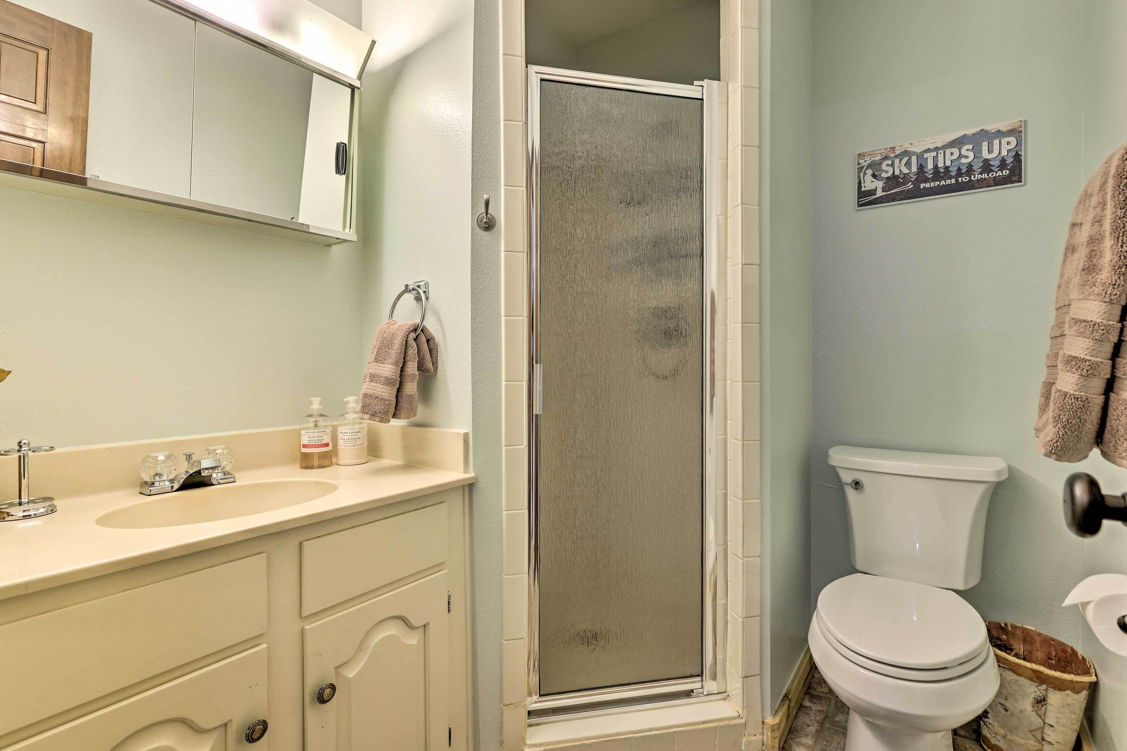 A bathroom with a shower, toilet, sink, and a towel rack.