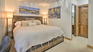 A bedroom with a large bed, two wall-mounted lamps, and two paintings depicting nature scenes. - Walk to Ski Lift: Breckenridge Retreat w/ 2 Decks! (Breckenridge)