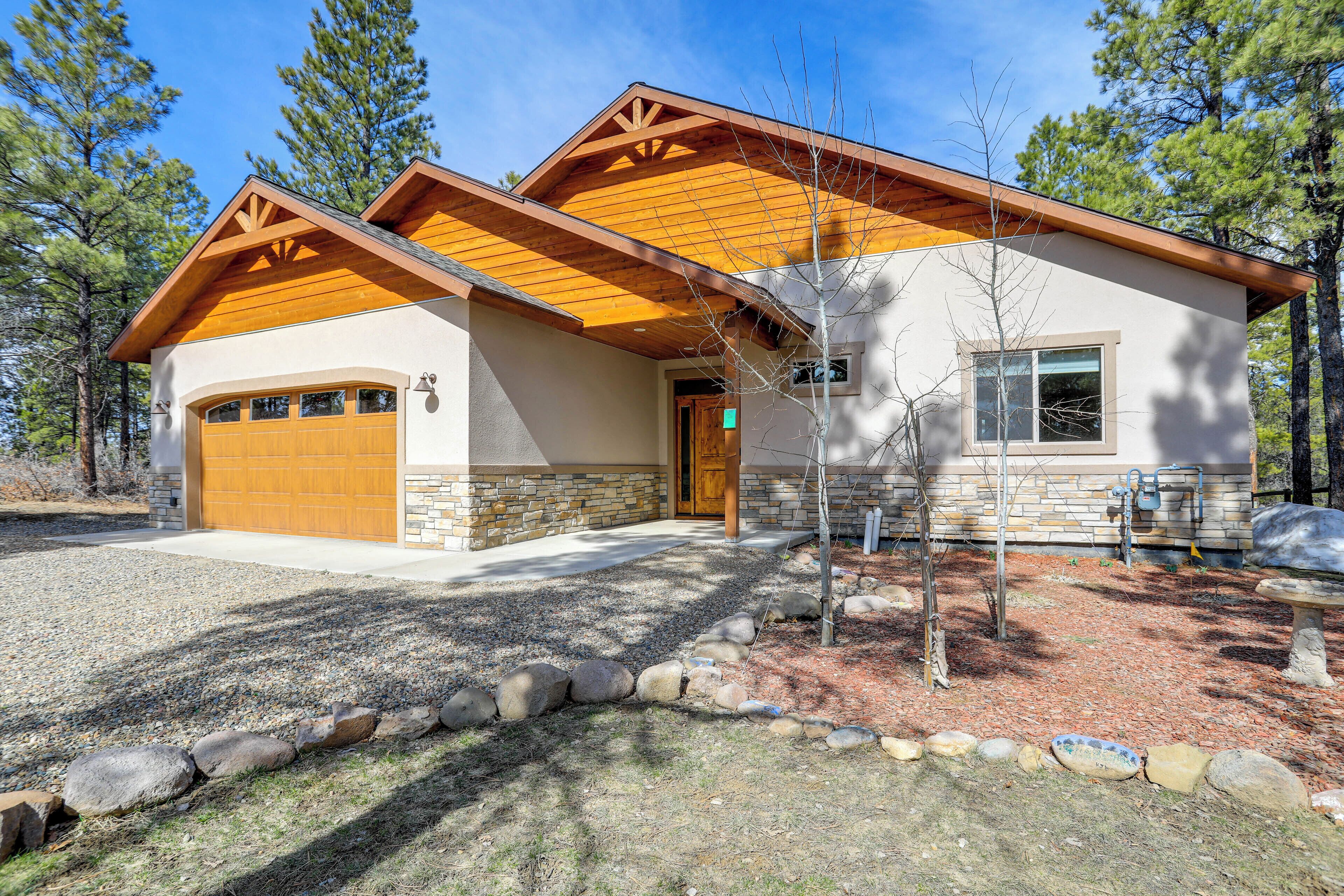 A two-story house with a garage, wooden beams, and a stone foundation.