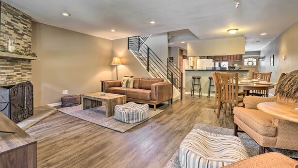 A spacious living area with a wooden floor, a leather sofa, a dining table, and a kitchen in the background. - Cozy Vail Condo ~ 4 Mi to Vail Ski Resort! (Vail)