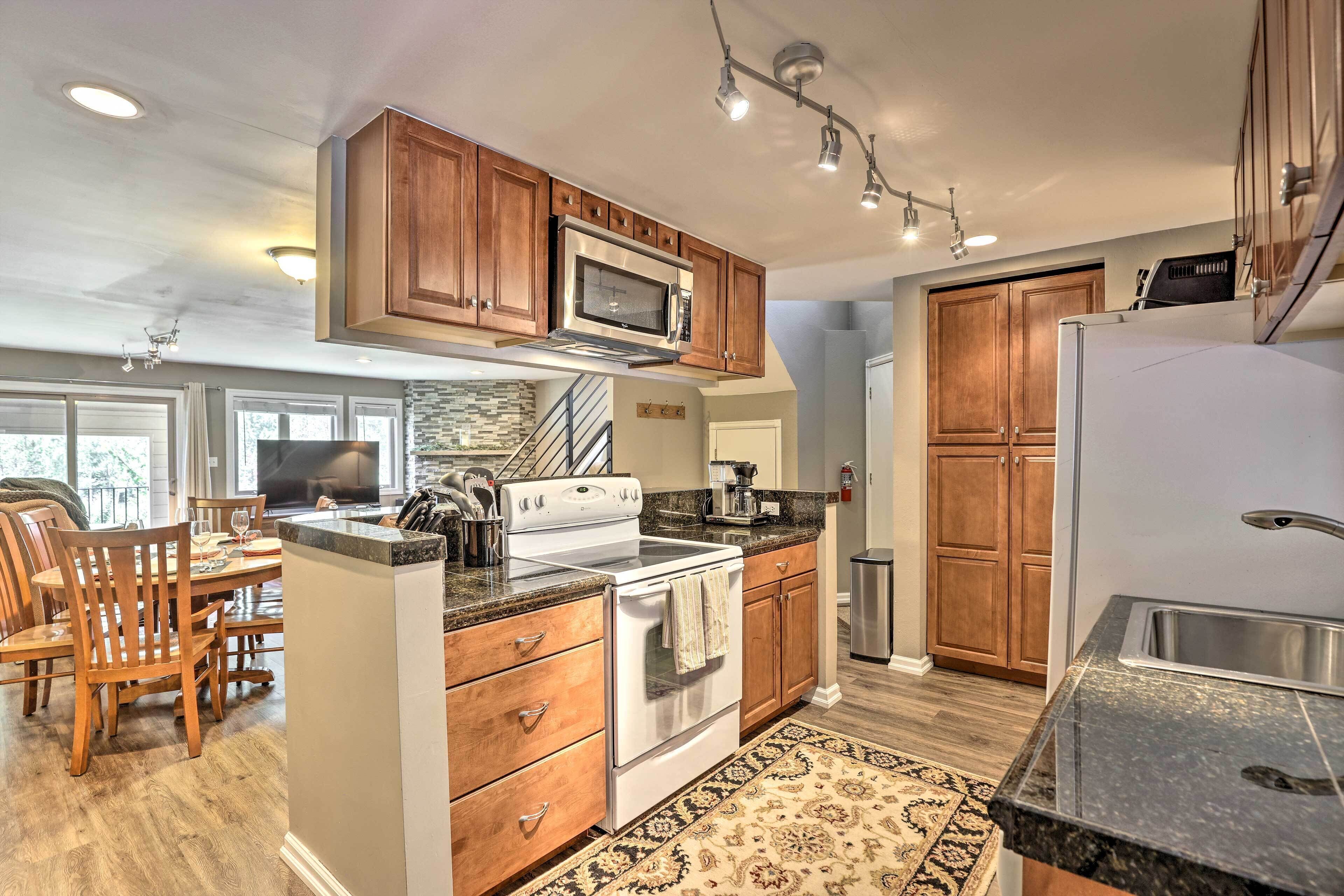 A modern kitchen with wooden cabinets, stainless steel appliances, and a dining area with wooden chairs and a table.