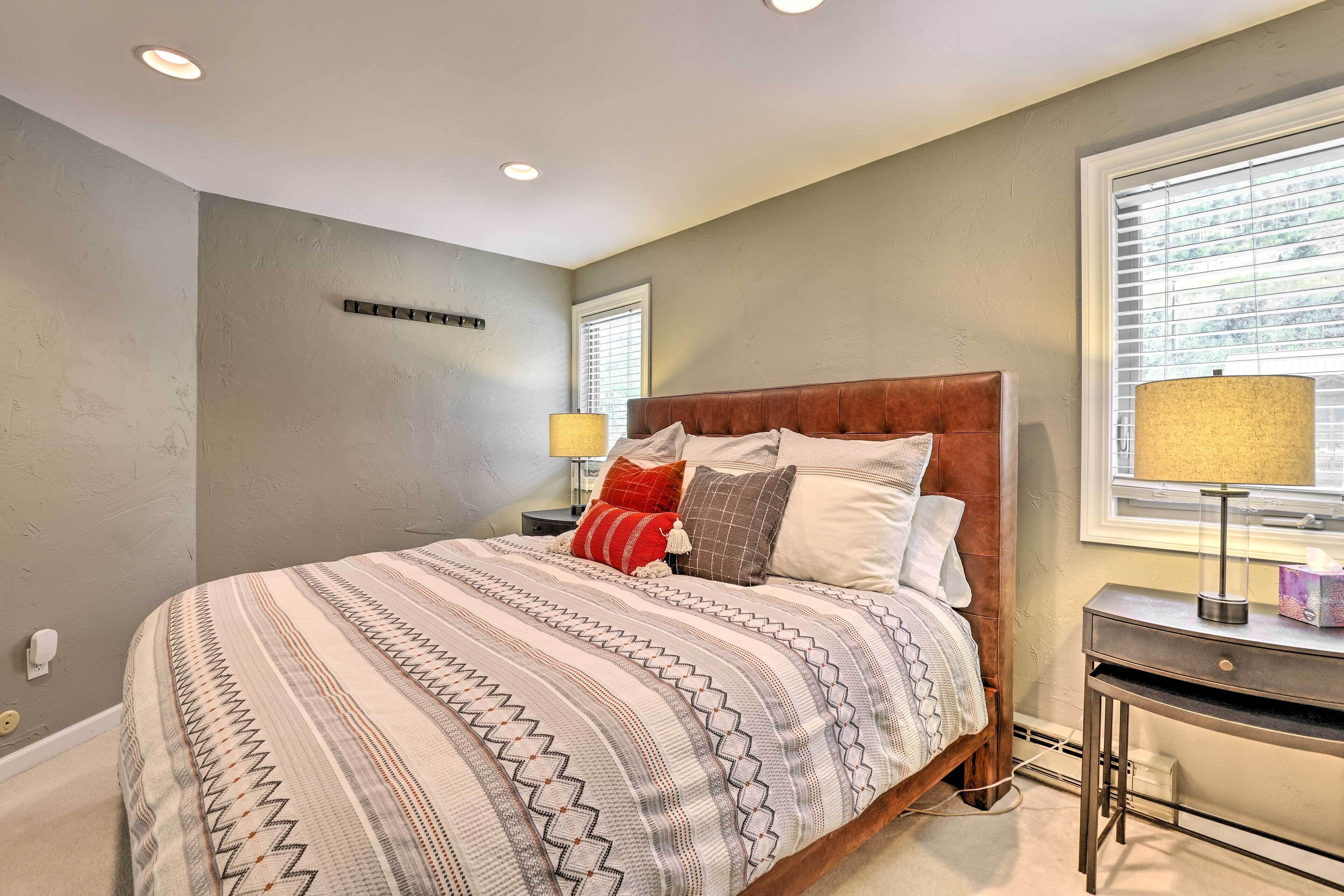 A bedroom with a bed, bedside tables, and a window with blinds.