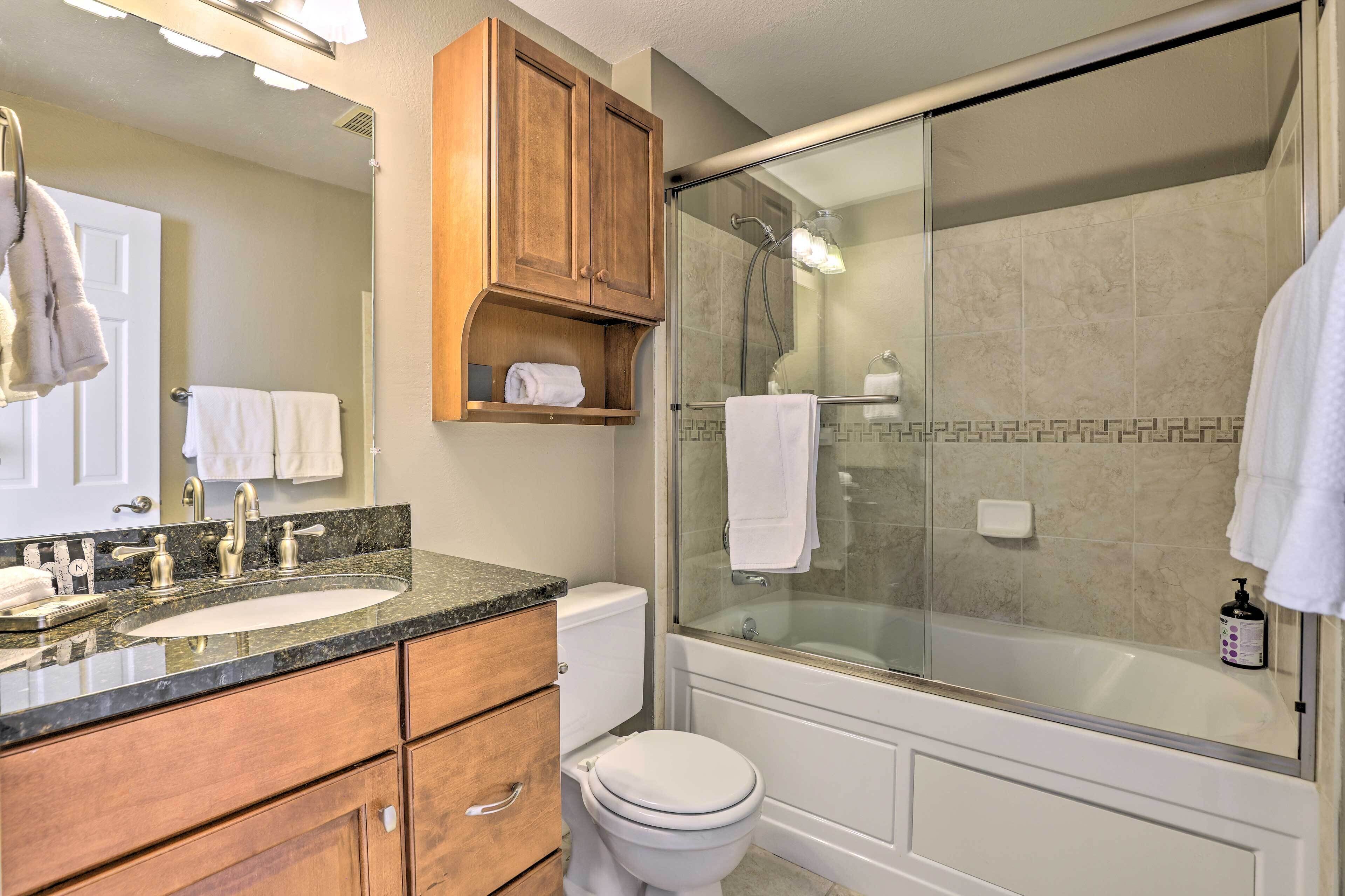 Une salle de bain avec deux vasques, des toilettes, une douche à parois de verre et des meubles en bois.