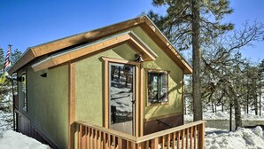 Une petite cabane avec une terrasse en bois, entourée de neige.