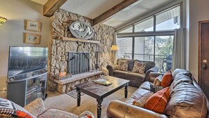 A cozy living room with a stone fireplace, leather sofa, and a flat-screen TV.
