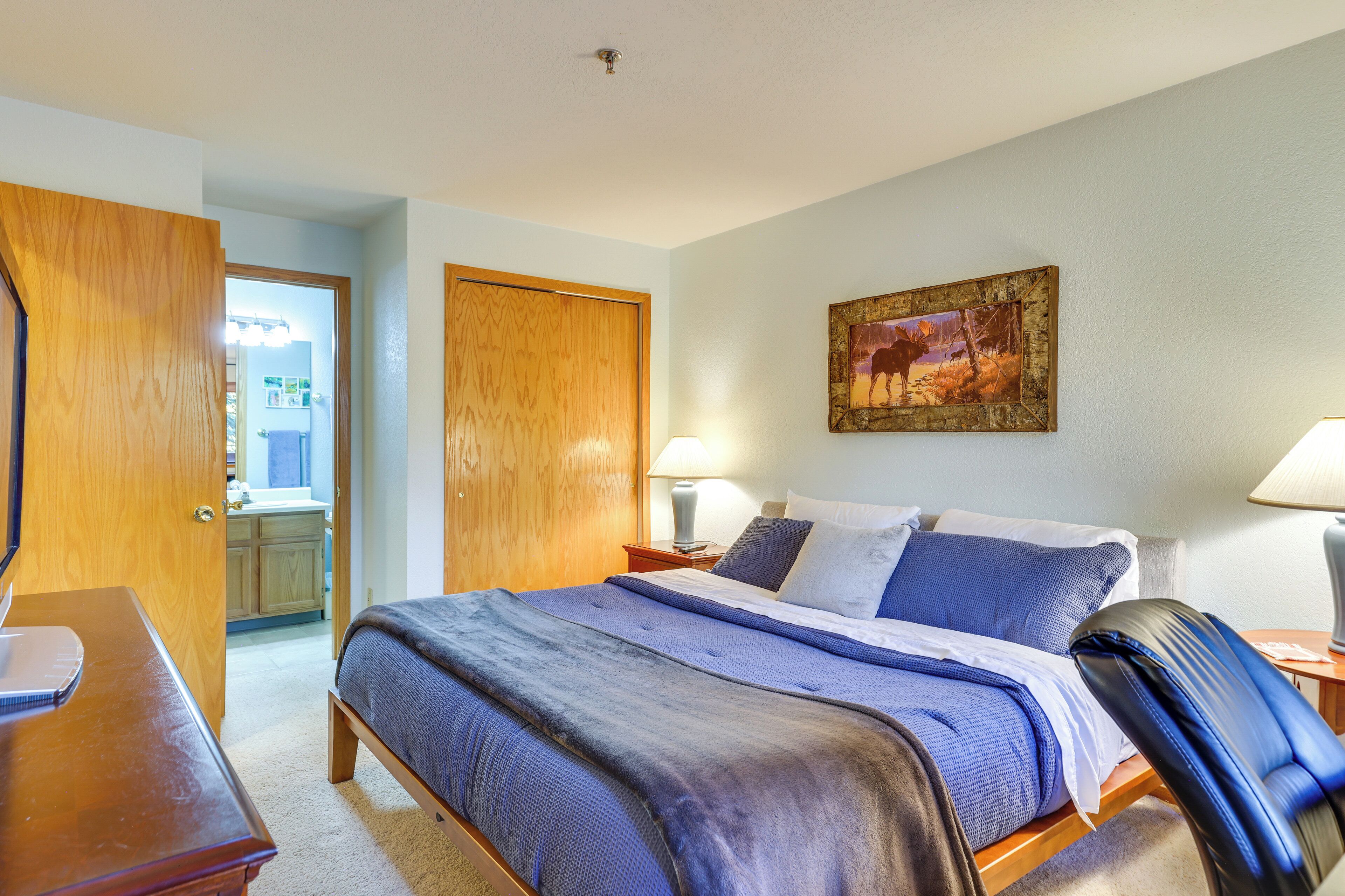 Une chambre d’hôtel avec un lit, un bureau, une chaise et un tableau au mur.
