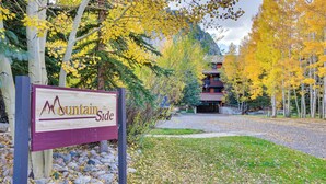 A wooden sign with "Mountain Side" written on it, surrounded by autumn foliage and a building in the background. - Walkable Frisco Condo: Mtn Views & Shared Hot Tub! (Frisco)