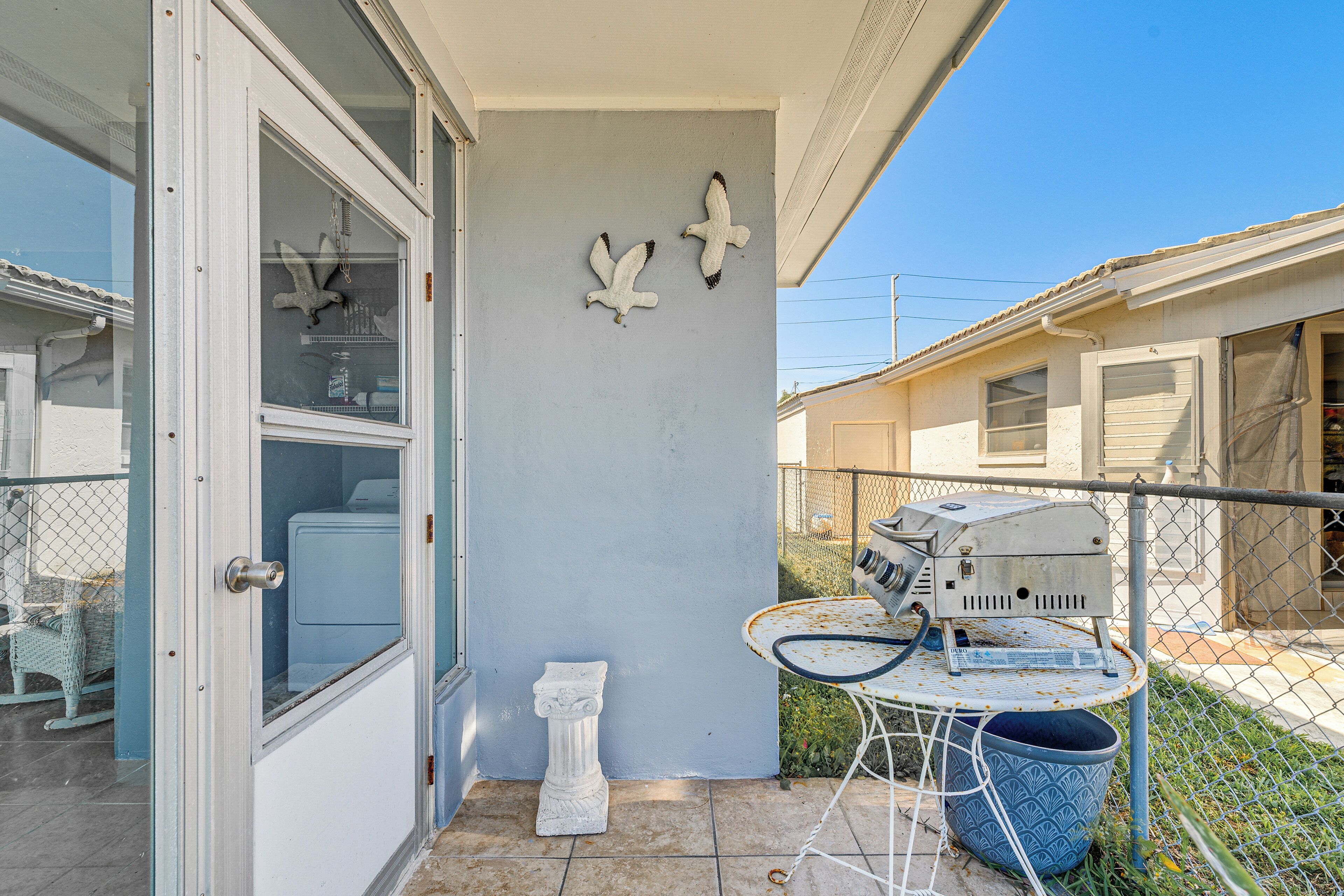 A patio with a washing machine, a small statue, and a table with a hose.