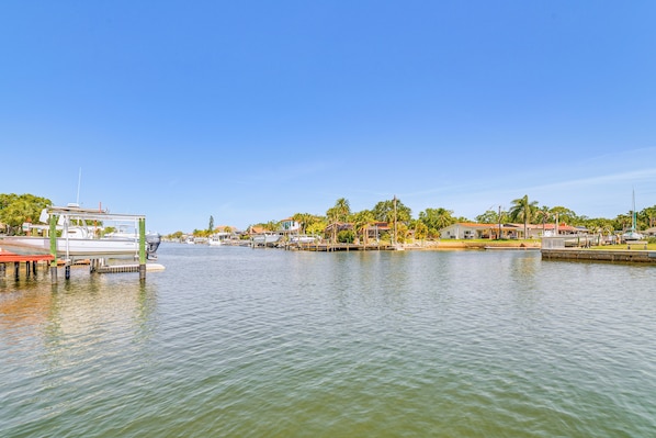 A marina with boats docked, a clear sky, and residential buildings along the waterfront.