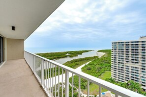 A balcony with a view of a river, greenery, and a building. - Beachfront Marco Island Condo w/ Pool Access! (Marco Island)