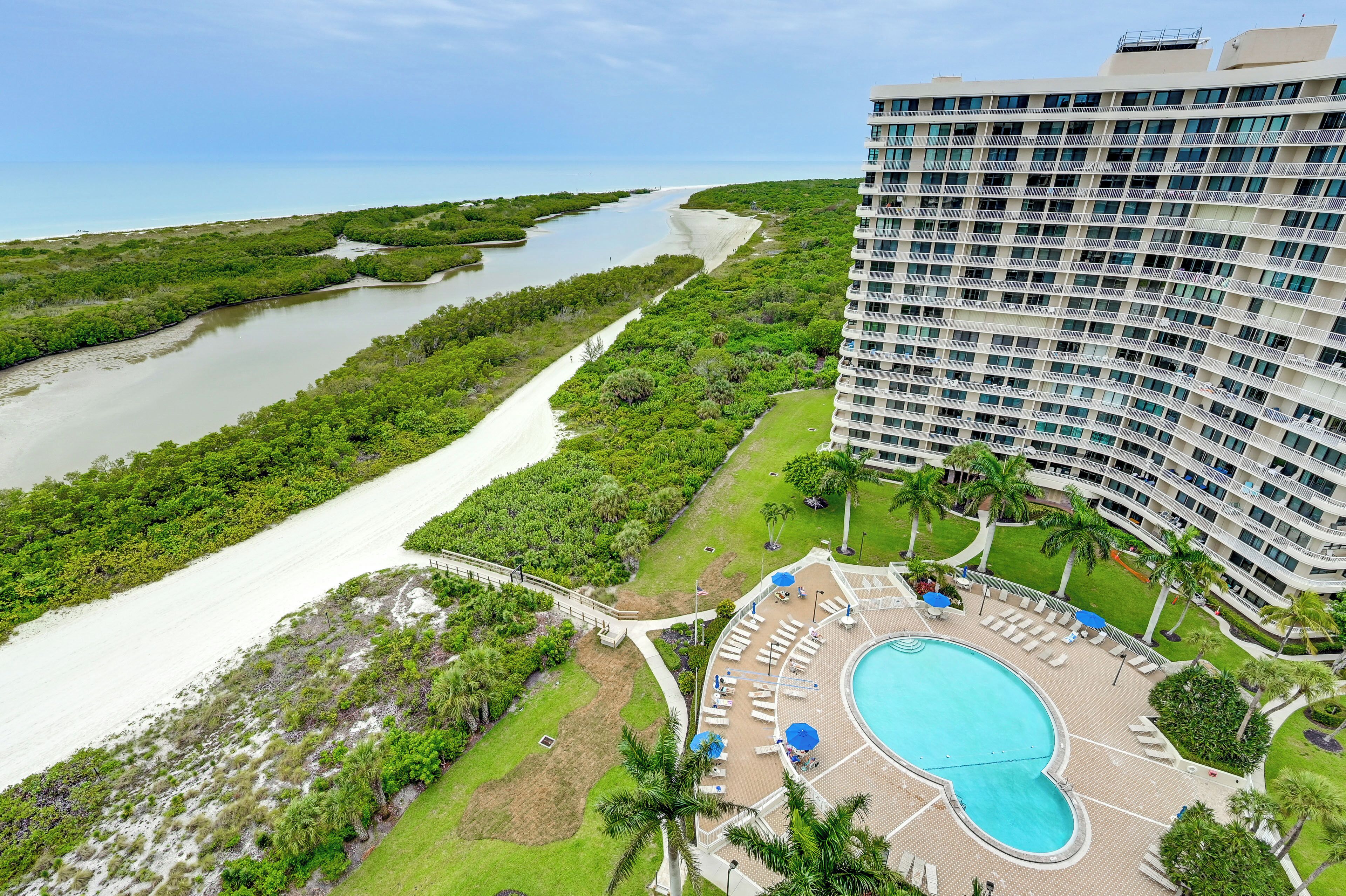 A hotel with a pool, surrounded by greenery and a river.