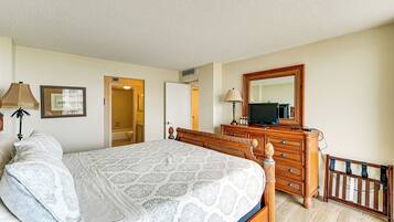 A bedroom with a bed, dresser, mirror, and a crib.