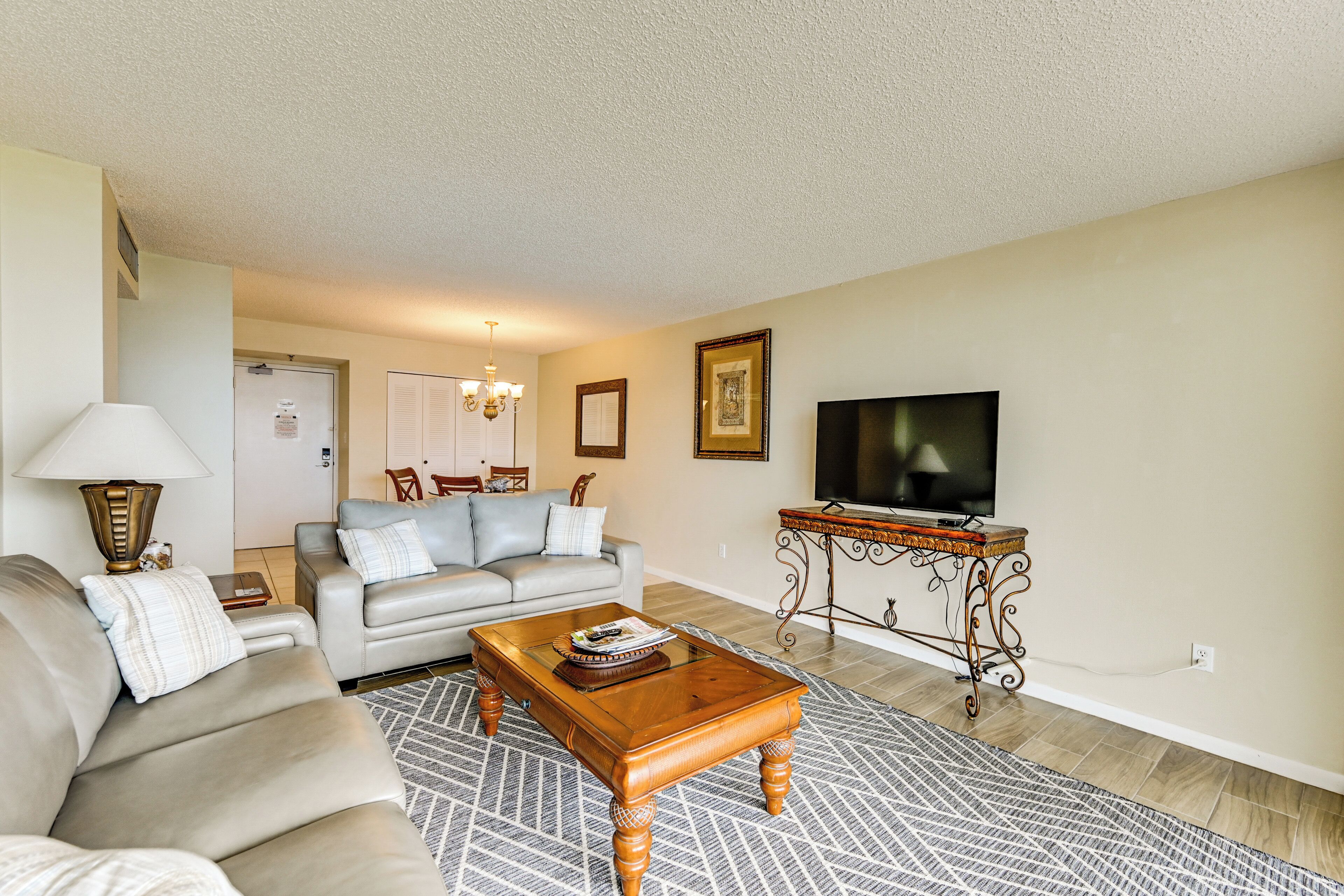 A living room with a sofa, a coffee table, a TV, and a patterned rug.