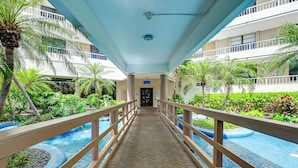 A corridor with a pool on either side, leading to a building entrance. - Beachfront Marco Island Condo w/ Pool Access! (Marco Island)