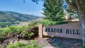 Un panneau indiquant « BEACON HILL », avec en arrière-plan un paysage vallonné et un bâtiment.