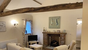 A cozy living room with a fireplace, a television, and two armchairs. - Puddleduck Cottage (Pickering)